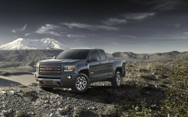 A GMC truck is parked on rocky terrain with mountains visible in the background, HD Desktop Wallpaper