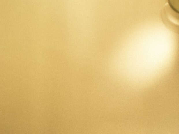 Shiny gold foil surface with smooth metallic texture and reflective light spots