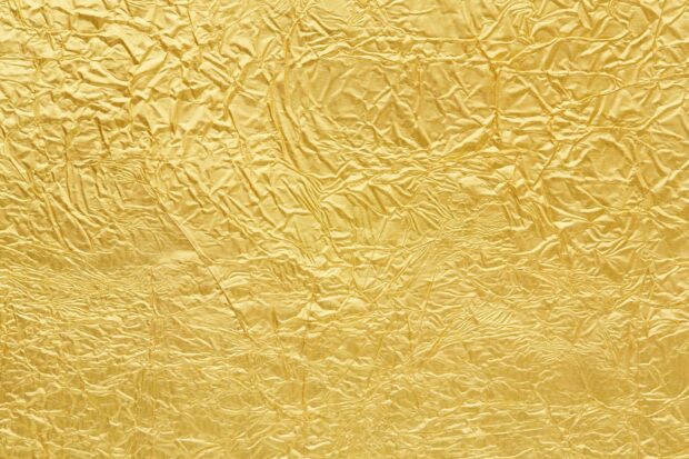 Crumpled gold foil texture with shiny reflective surface and intricate folds