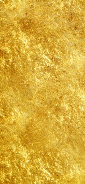 Shiny gold foil texture with rough patterns on a vertical surface