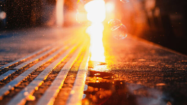 Golden light reflections on wet textured pavement in urban setting