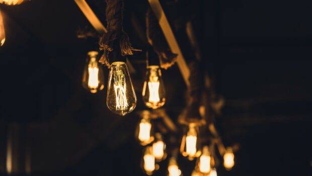 Warm glowing gold lights hanging from ropes in a dark room