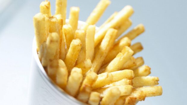 A close up of crispy golden French fries served in a white container, HD Desktop Wallpaper