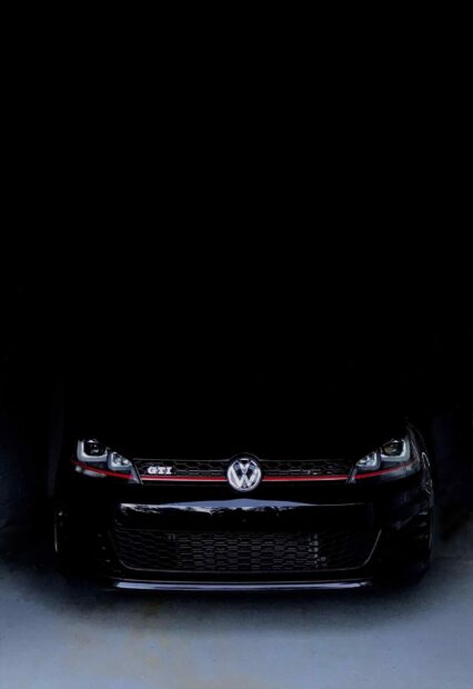 Chiếc Golf Gti màu đen phô bày lưới tản nhiệt phía trước đặc trưng và logo trong bối cảnh tối, Hình nền di động 2K