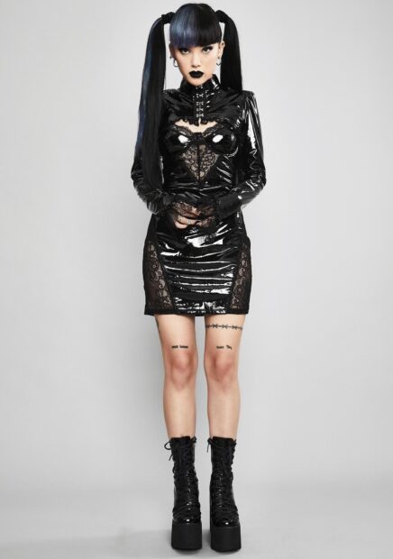 Goth style model wearing black vinyl dress and platform boots with long black hair in pigtails