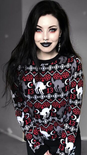 A goth girl wearing a black sweater with cats and occult symbols in a stylish design
