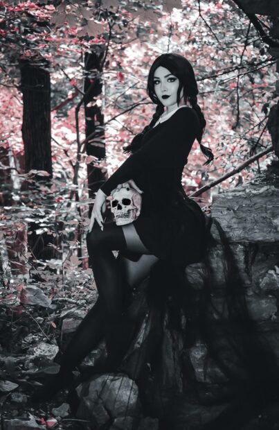 Goth girl holding skull in dark forest with gothic style and makeup