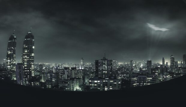 The Gotham skyline at night with illuminated buildings and dark clouds in the sky