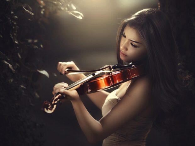 A woman focused on playing the violin with gentle lighting and dark background, HD Desktop Wallpaper