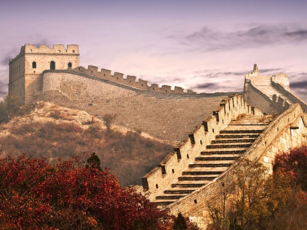 The Great Wall of China winding over autumn hills under a dramatic sky