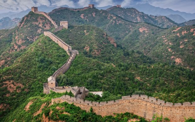 Ancient Great Wall Of China stretching over green mountains in a scenic landscape