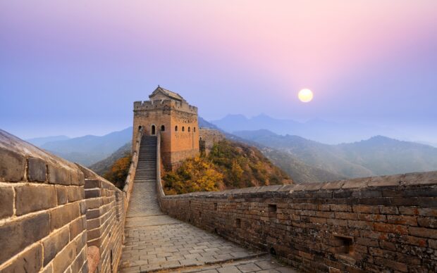 The Great Wall Of China winding through mountains under a colorful sunset sky
