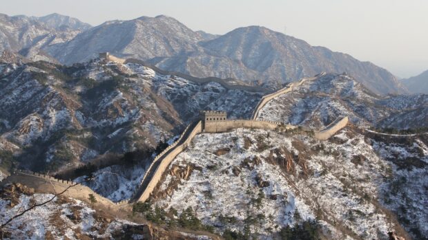 Great wall of china winding over snow covered mountains in winter scenery