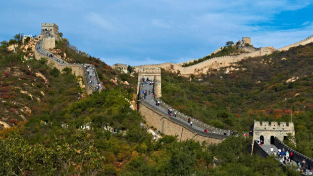 The Great Wall of China winding over hills with tourists walking along the historic landmark