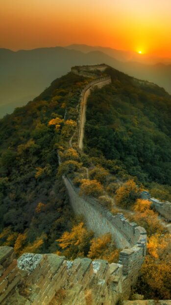 Great Wall Of China winding along a mountain ridge at sunset surrounded by autumn foliage