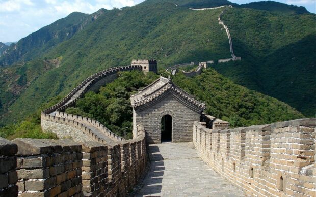 Great Wall Of China winding through green mountains in a clear sky scene