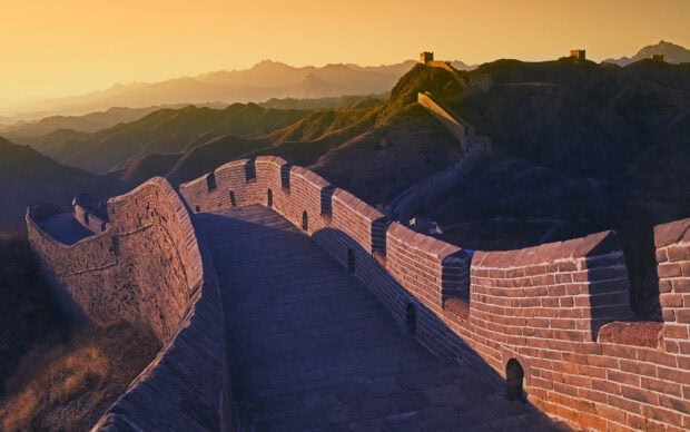 The Great Wall Of China stretches over mountain ridges under a warm sunset light