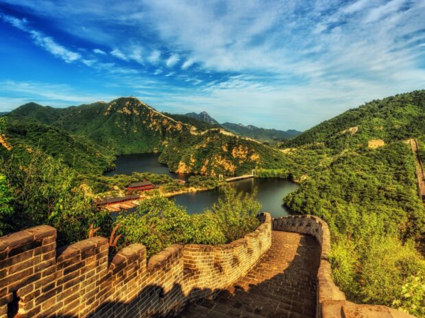 The Great Wall of China winding through lush green mountains under a blue sky