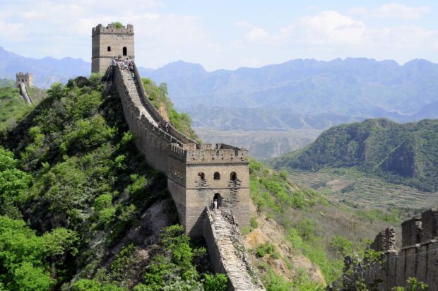 Ancient architecture of Great Wall of China stretches across green hills