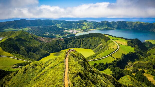 A group of people stand on a pathway overlooking green hills and lakes, 4K Desktop Wallpaper