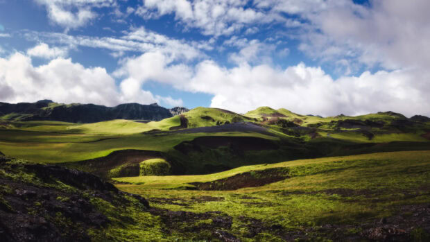 A scenic view of green hills with cloudy skies and rocky terrain, 4K Desktop Wallpaper