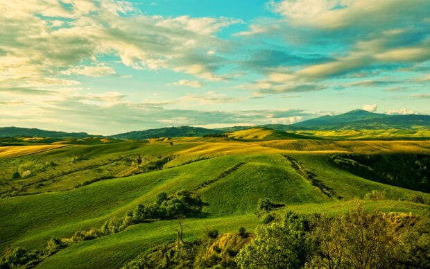 Green hills under a partly cloudy sky with lush vegetation, 2K Desktop Wallpaper