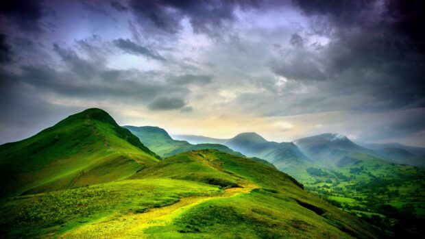 A scenic view of green hills stretching across the landscape under a dramatic cloudy sky, 4K Desktop Wallpaper