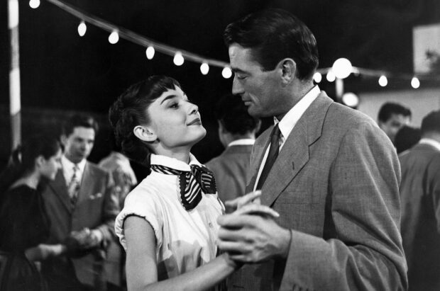 Gregory Peck shares a dance with a woman under string lights in a classic movie scene, HD Desktop Wallpaper