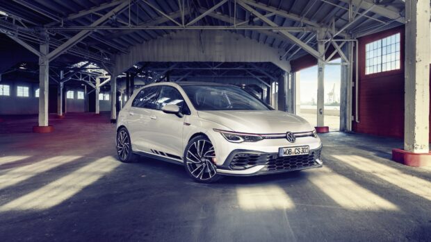 A white Gti car parked inside an industrial warehouse with sunlight streaming through large windows