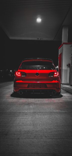 Red Gti hatchback car rear view parked under streetlight at night