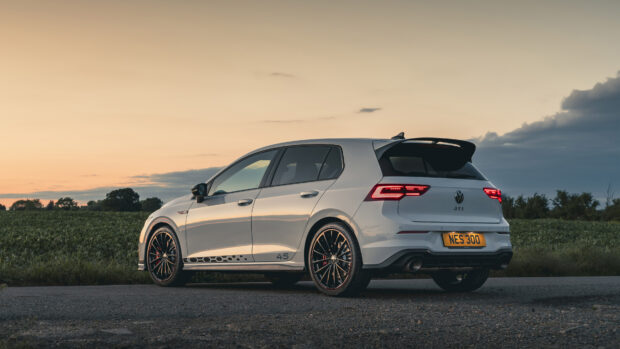 A white Gti car parked on a rural road at sunset with scenic fields in the background