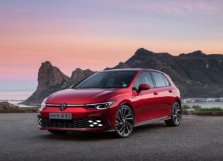 Red Volkswagen Golf 8 GTI car parked in front of mountain landscape at sunset