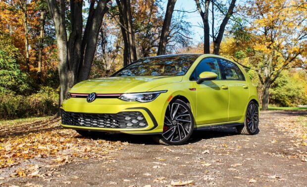 Bright yellow Gti parked on autumn road surrounded by trees with fallen leaves