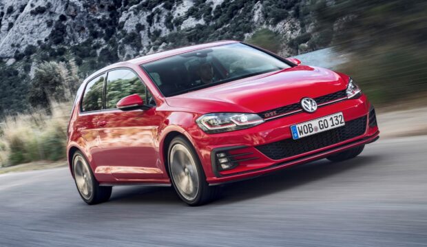 Red Volkswagen Gti car driving fast on mountain road with blurred background