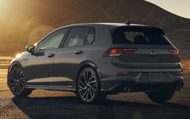 A high quality GTI hatchback parked on a sunlit road near mountains