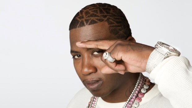 Gucci Mane with patterned haircut wearing jewelry and posing with hand near face