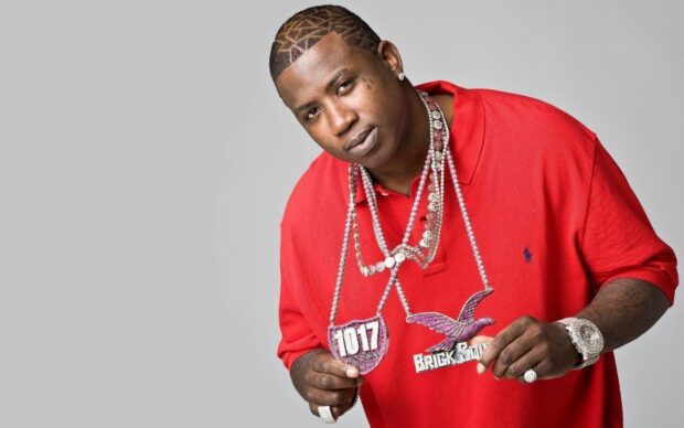 Gucci Mane wearing a red shirt and holding diamond chains in a studio setting