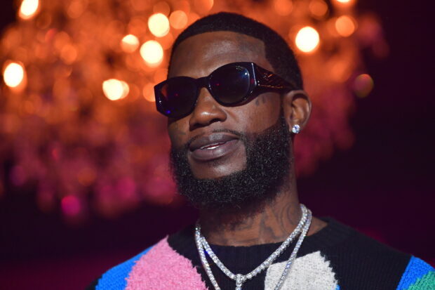 Gucci Mane wearing sunglasses and diamond chains in a colorful sweater