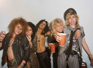 Guns N Roses band members posing together in a casual setting with cigarettes and drinks