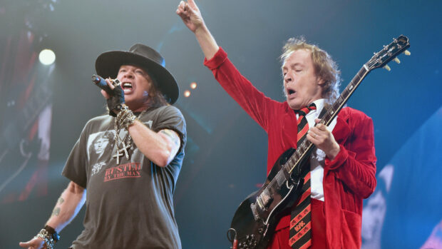 Guns N Roses performing live on stage with guitar and microphone during a concert