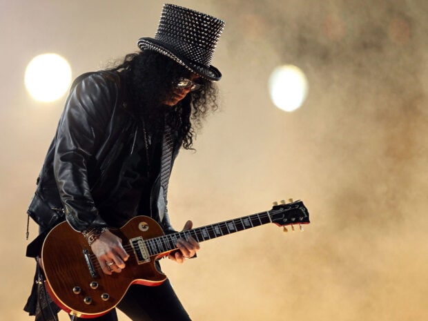 A Guns N Roses guitarist playing an electric guitar on stage under bright lights