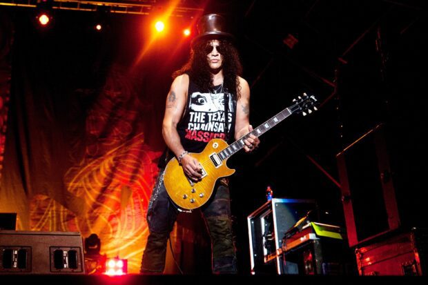 A guitarist from Guns N Roses performing live on stage with a yellow electric guitar