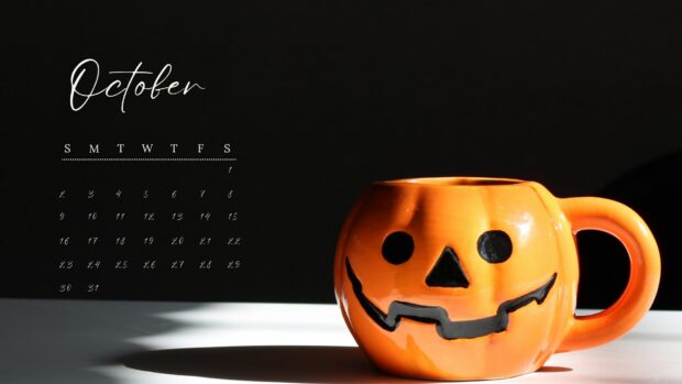 A jack o' lantern mug sits next to an October calendar for Halloween 2025