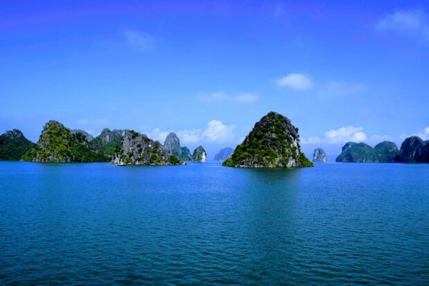 Limestone islands covered with lush greenery in Halong Bay under a clear blue sky