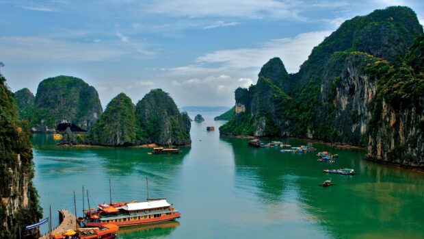 Traditional boats sailing between towering limestone islands in Halong Bay