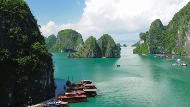 Scenic Halong Bay with green limestone islands and wooden boats floating on turquoise water