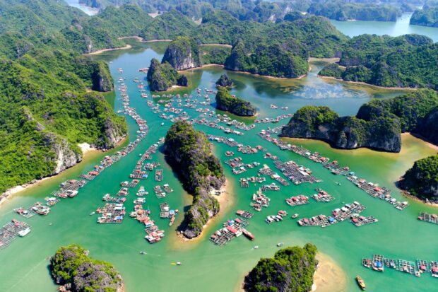 A scenic view of Halong Bay with lush green islands and floating fishing villages in clear blue water