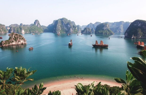 A tranquil scene of Halong Bay with traditional boats and limestone islands surrounded by clear blue water