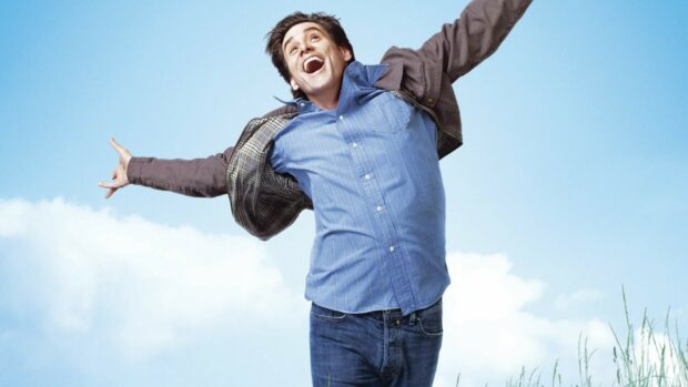 A joyful Jim Carrey jumping outdoors against a blue sky, HD Desktop Wallpaper