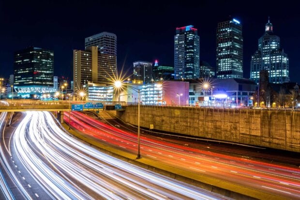 Nighttime Hartford skyline with illuminated buildings and busy highway traffic trails